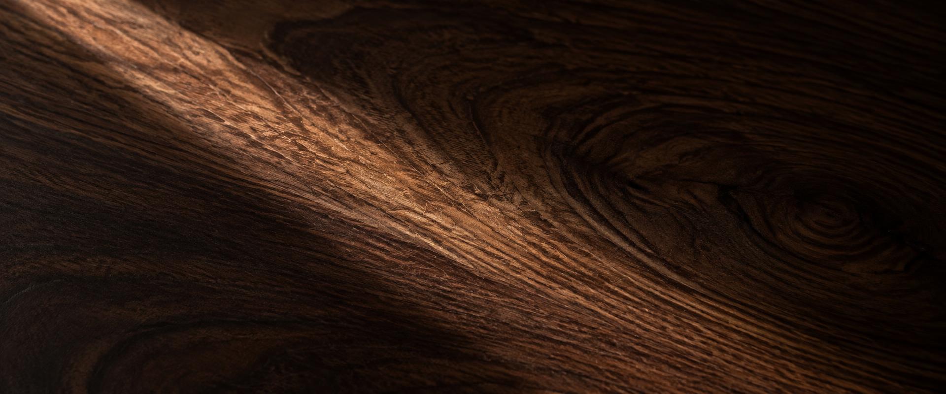 Close detail of dark walnut grain crossed by a shaft of light